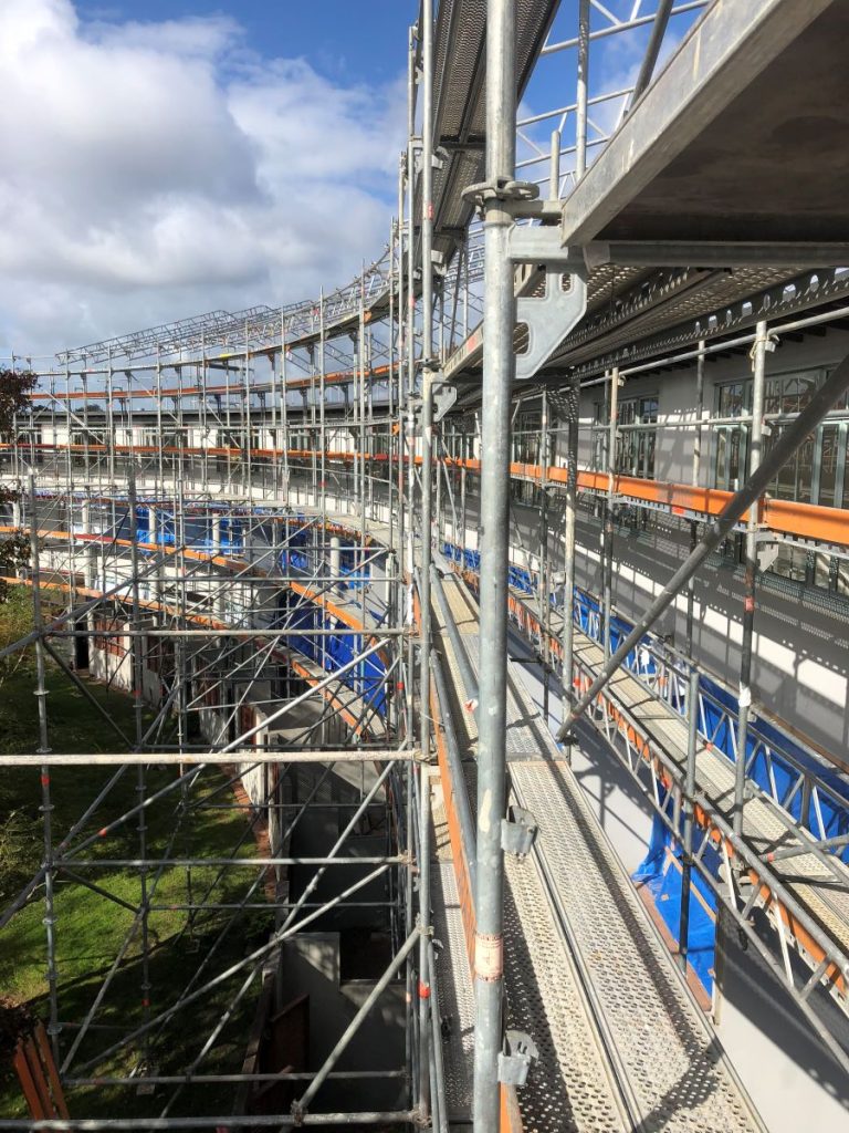 Detailed view of a large scaffold structure supporting a construction site under a clear sky.